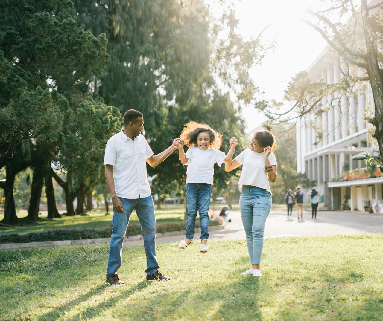 who-we-are Joyful family enjoying a playful day at the park, embracing love and togetherness under the summer sun.