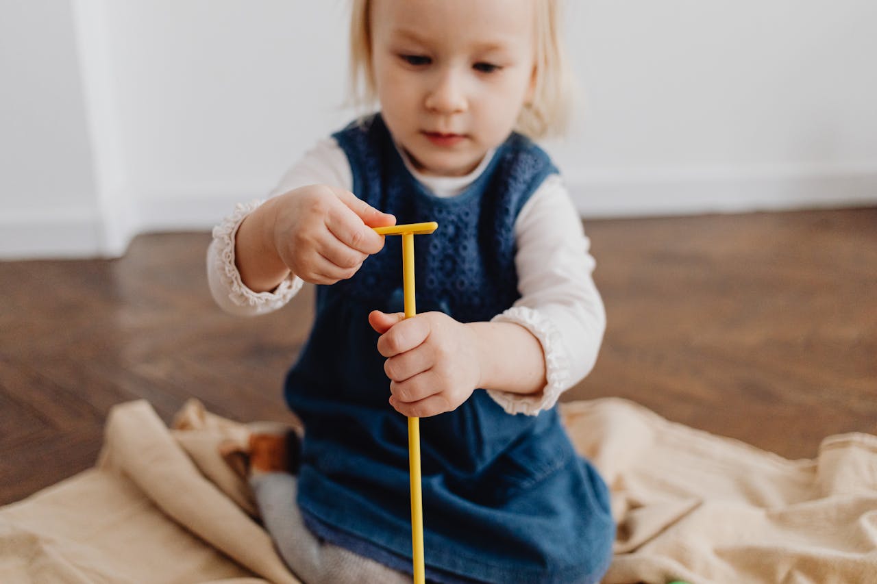 journey A young child playing indoors with a yellow stick, fostering creativity and imagination.